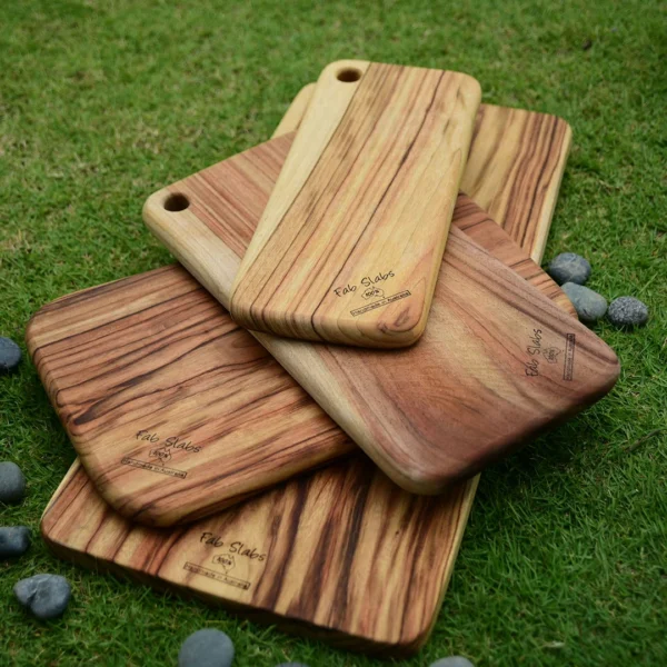 A group of four wooden cutting boards on top of grass.